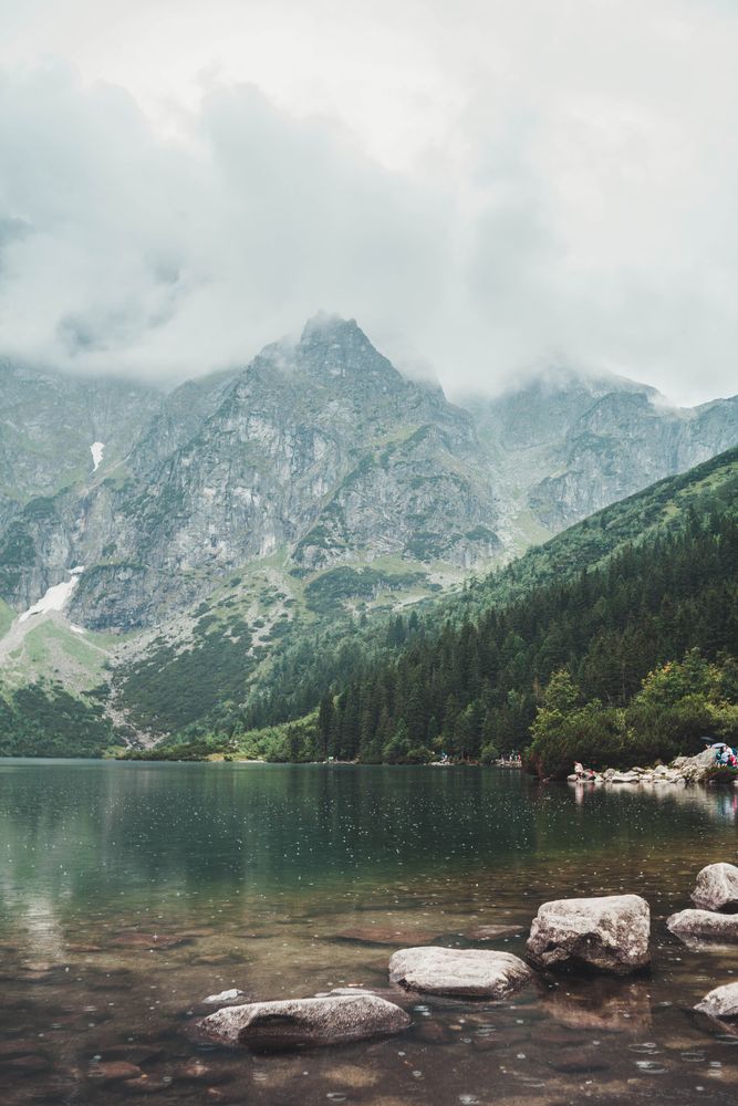 Lake beside mountain under sky full of clouds