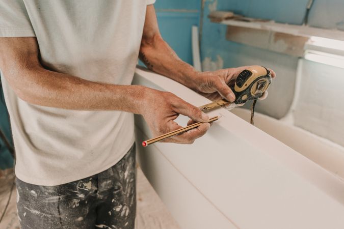 Man in respirator measuring surf board in workshop