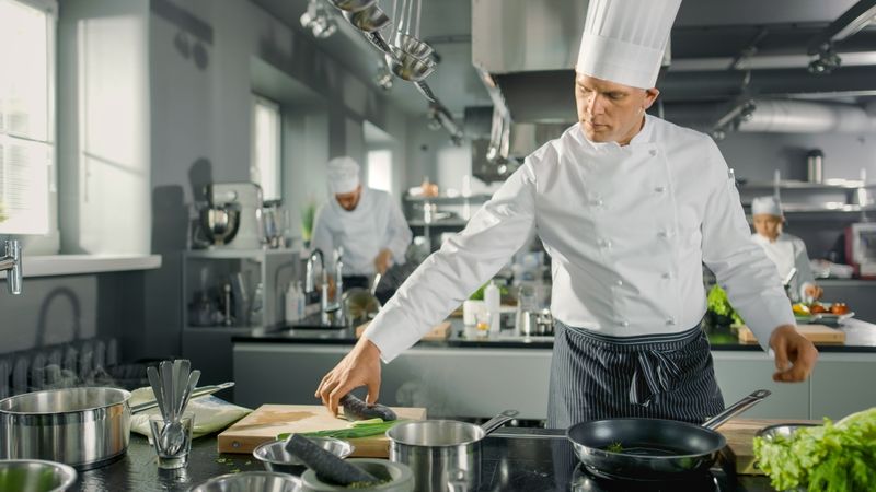Famous Restaurant Chef Takes and Puts Fish on a Hot Pan. He Works in a Modern Kitchen.