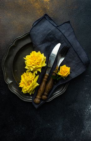 Dark table setting with yellow roses and chopsticks