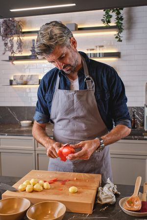 Man peeling tomato in kitchen