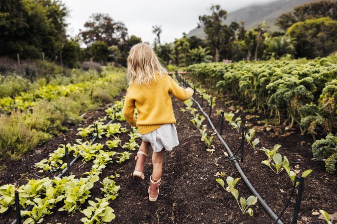 Young blonde girl walking through an organic farm during the day