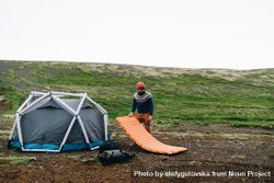 Man setting up bed tent in field 0Lvey4