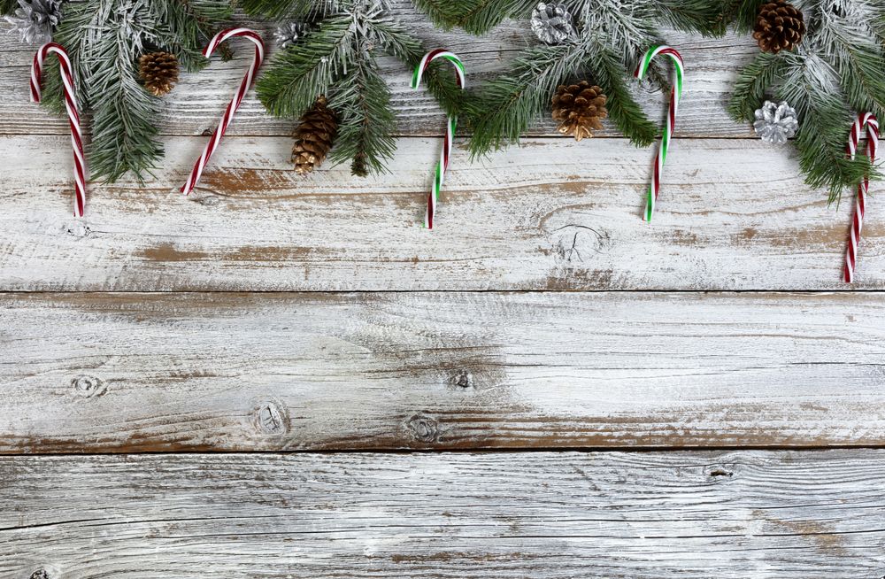 Snow covered fir tree branches with gold and silver pine cone decoration ornaments on rustic wood