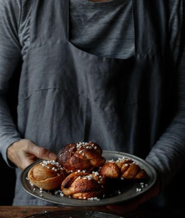 Crop female holding plate with cardamom buns