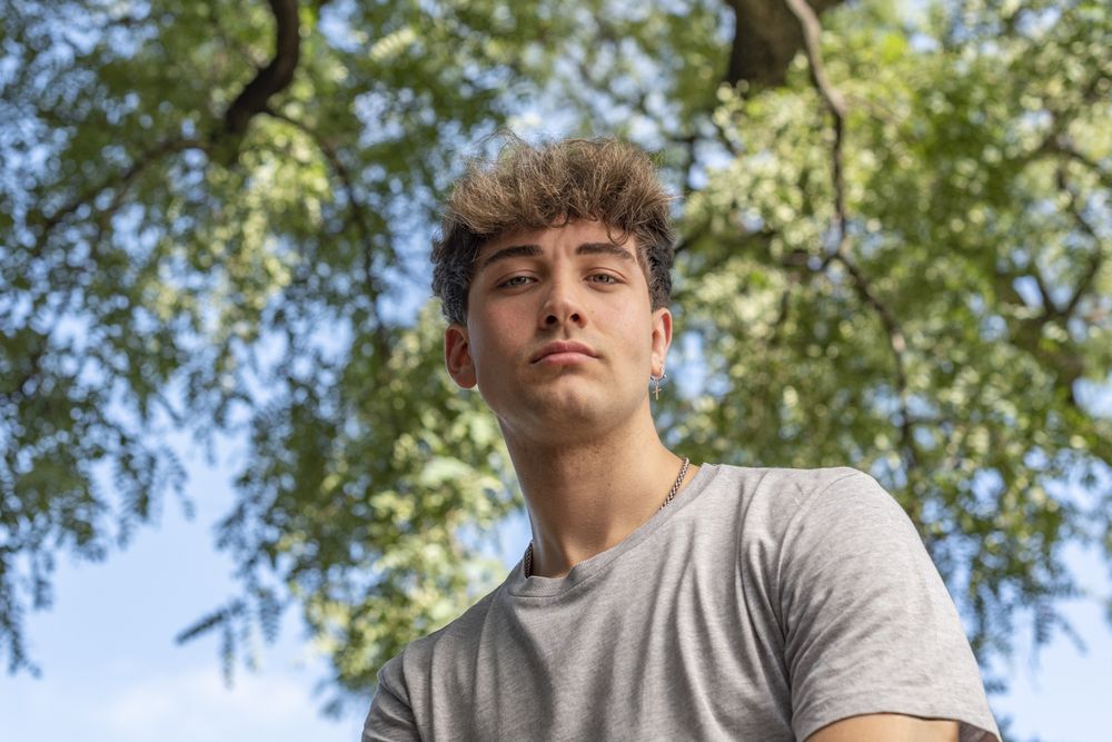 Low angle of a young man, serious, looking at the camera in a pu