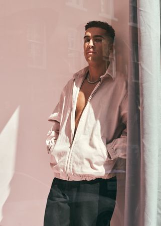 Stylish man in light open jacket as seen through the window