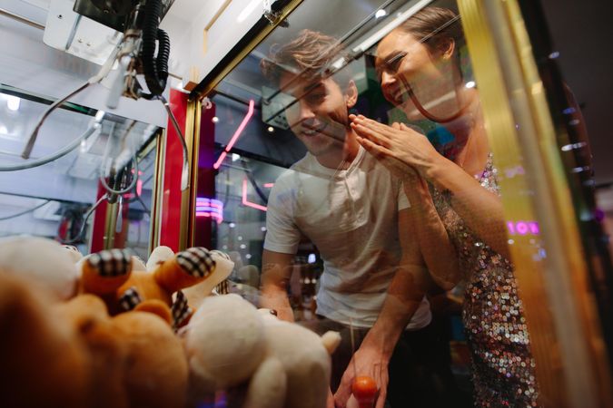 Happy couple having fun playing coin operated games at a gaming parlour