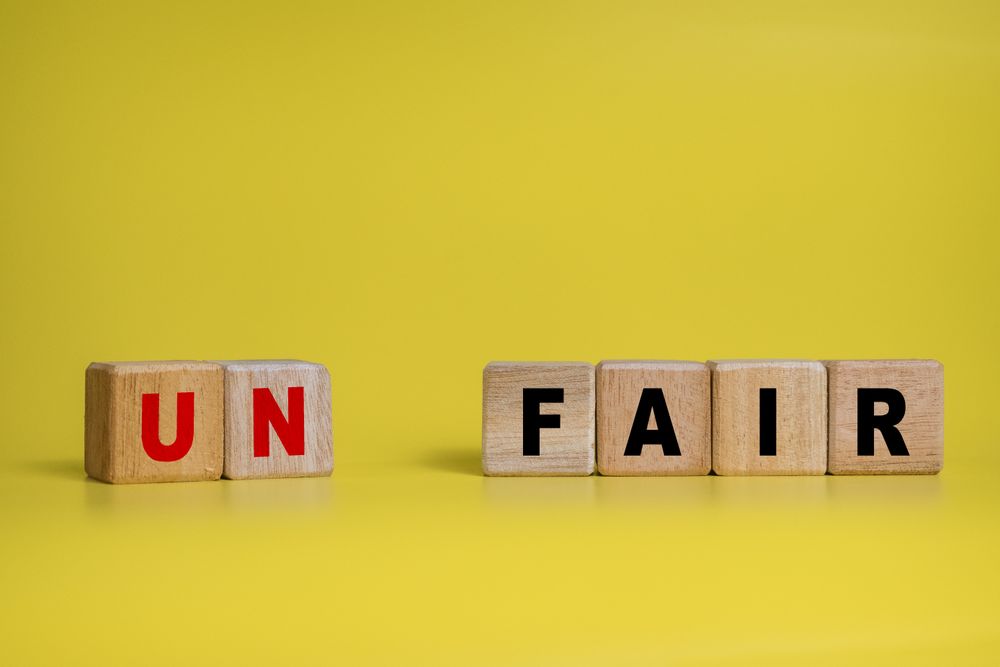 un and fair separated words on wooden blocks isolated on yellow background. concept of fairness