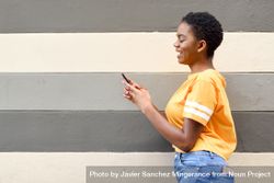 Smiling female checking phone in front of striped wall 4j2a94