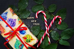 inscription of new year on a board with gift and red candy