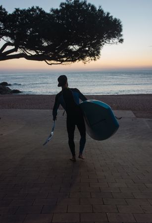 Man practicing paddle surfing with neoprene in a sunrise