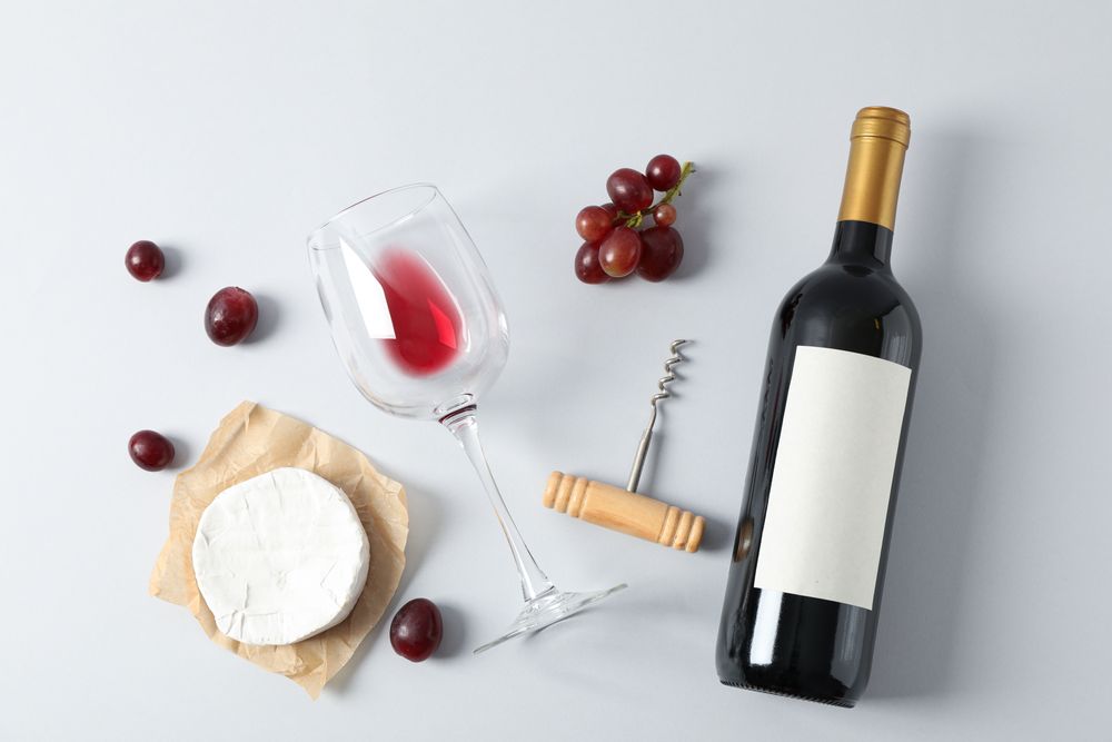 Flat lay. Grapes, cheese, corkscrew, bottle and glass with wine on grey background, copy space