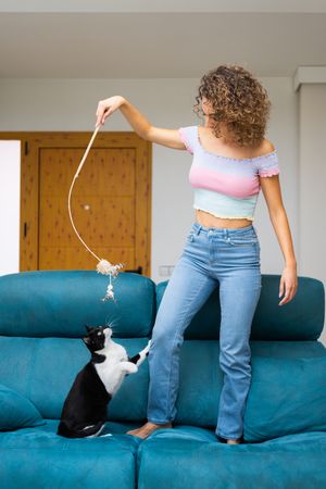 Woman playing with string toy with cat
