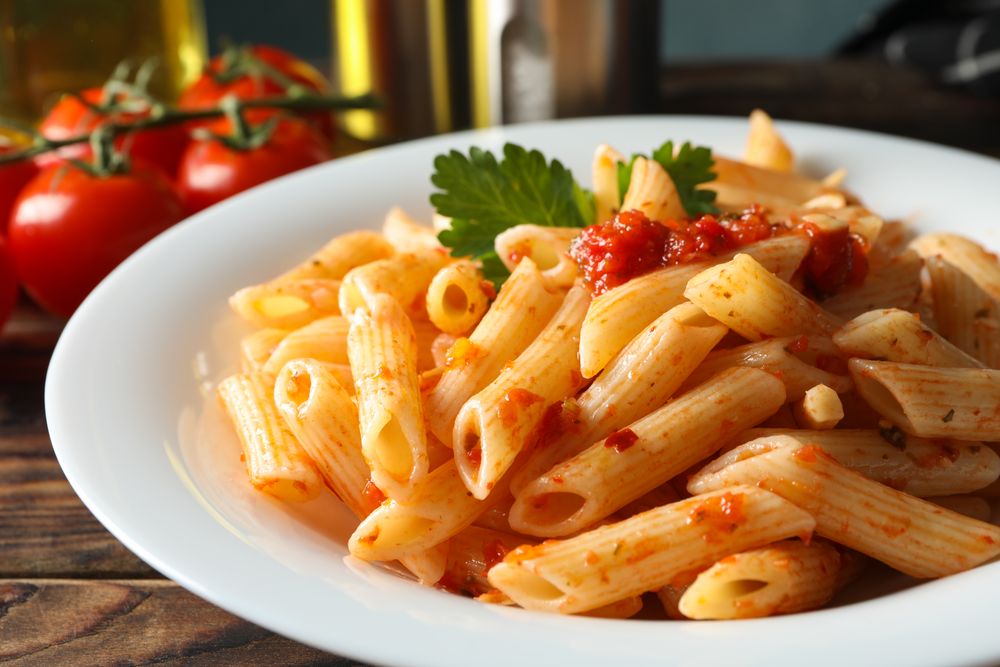 Composition with plate of tasty pasta on wooden background, close up