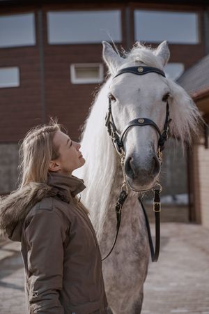 Warm dressed woman with gray horse outside