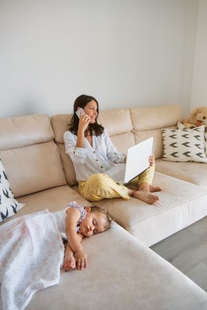 Woman talking on phone on couch near sleeping baby