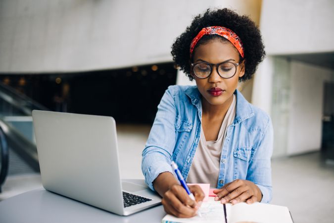 Woman taking notes from laptop at work