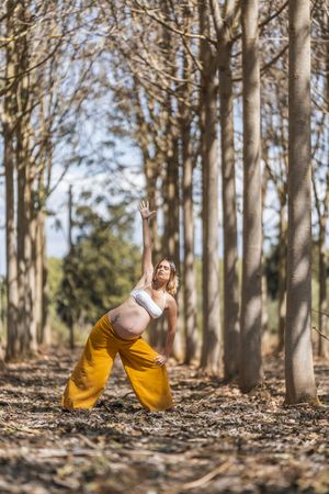 Concentrated adult expectant mother practicing yoga in park