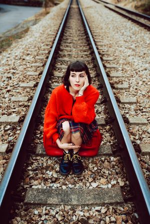 Woman sitting on sleepers in middle of railway