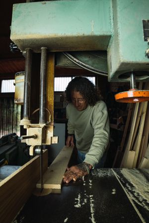 Mature male woodworker cutting plank with band saw