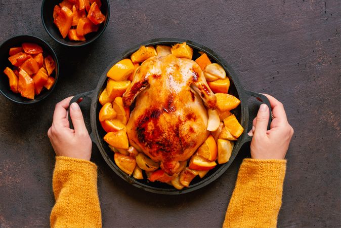 Person placing chicken in pot on table with veggie sides