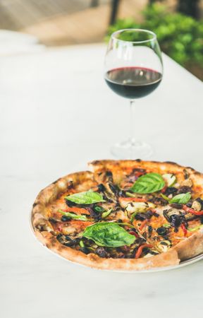 Wood fire oven cooked pizza with glass of red wine