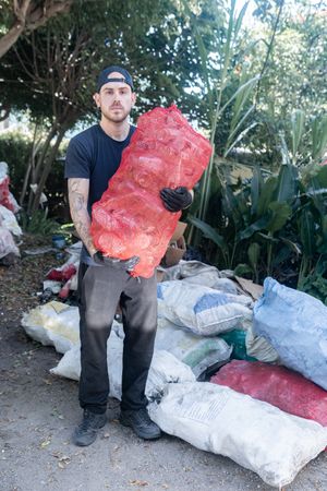 Young Man Holding Recycled Glass Bottle Sack at Recycling Plant. Portrait