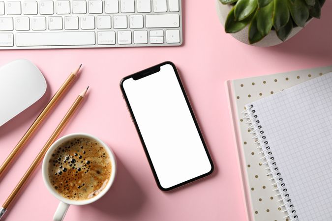 Workplace with phone with empty screen, top view