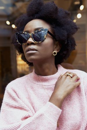 Black woman with sunglasses wearing pink sweater