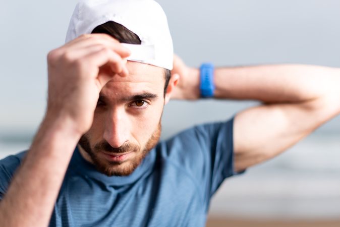 Confident male gymnast in active wear and cap on beach
