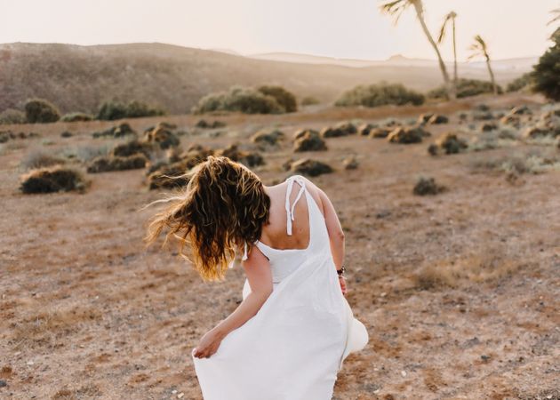 Woman in white dress in dry field in sunlight