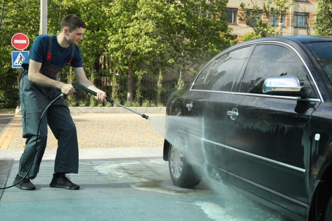 A man washes a car in a manual car wash. Clear car