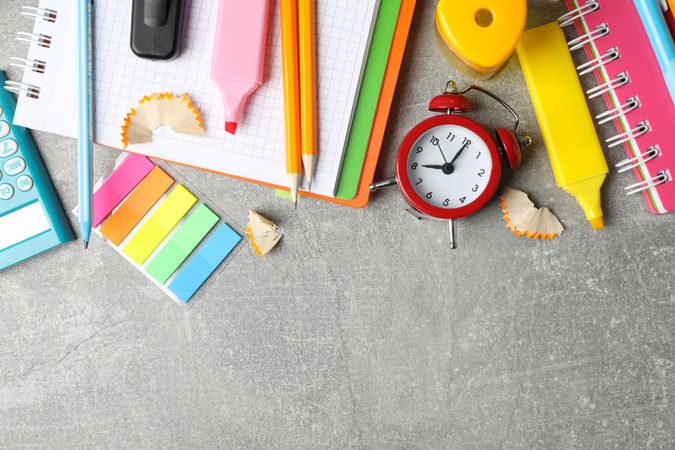 Grey desk with colorful stationary along the top with copy space