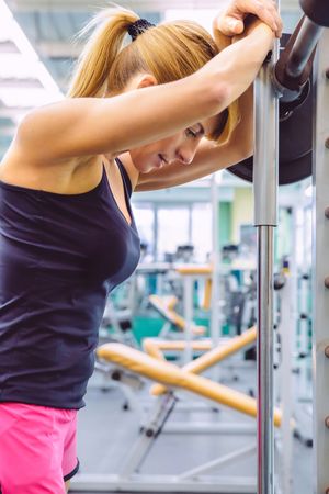 Fit woman leaning on barbell in between lifting