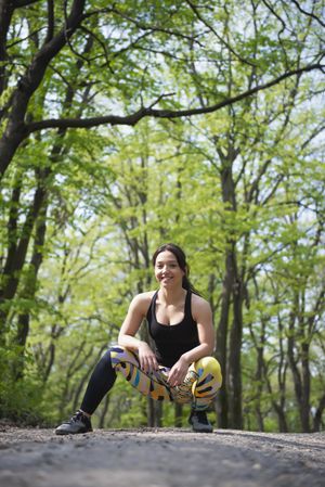 Female crouching down in forest in athletic gear