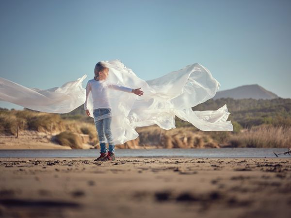 Preteen boy entangled in plastic film with raised hand