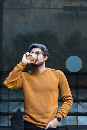 Man drinking takeaway coffee and looking away