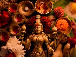 Buddha golden statue surrounded by diya and flowers