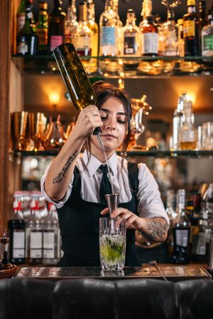 Female bartender preparing a cocktail in a traditional cocktail bar