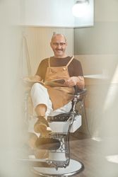 Stylish barber reading book in barbershop