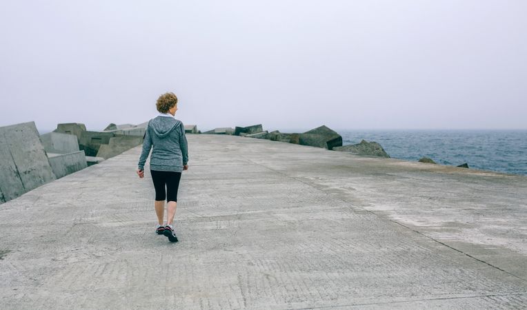 Back view of woman walking by sea pier