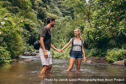 Loving young couple standing in forest stream 5raQ70