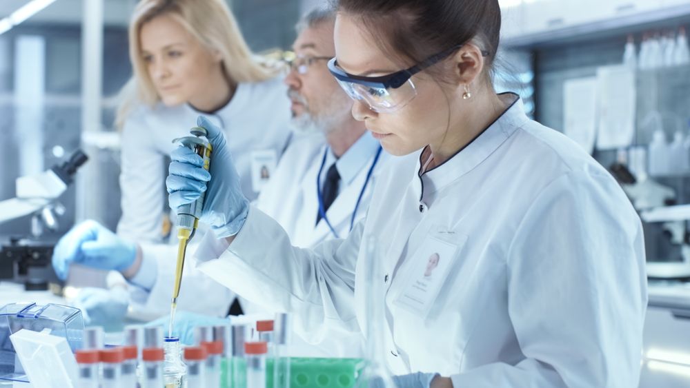 Team of Research Scientists Working With Personal Computer, Analysing Test Trial New Generation Drug Data and Using Micropipette for Filling Test Tubes.