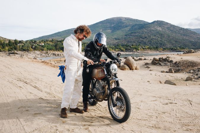 Two people with motorcycle checking directions on phone