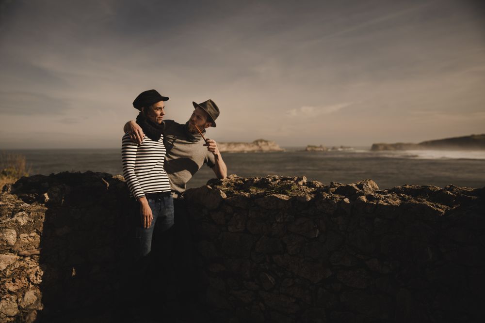 Man holding woman on hands near stones on shore