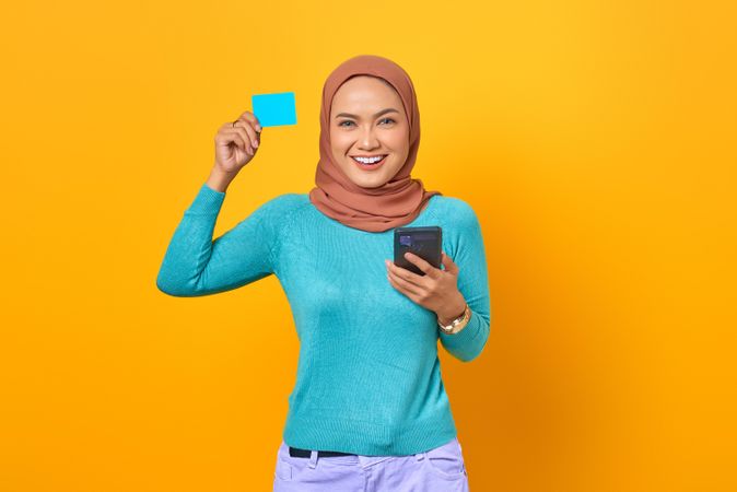 Muslim woman looking happy with credit card and smartphone