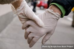 Two people wearing plastic gloves holding hands 4dk6l5