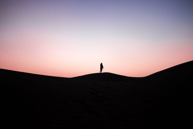 Silhouette of person standing on hill during sunset