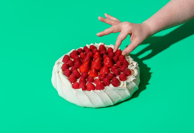 Pavlova cake with fresh berries isolated on a green background